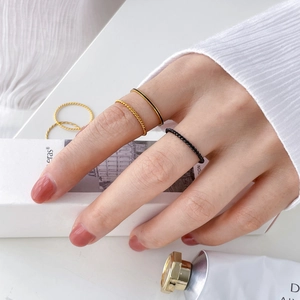 Close-up of minimalist gold twisted rope rings and black enamel hexagon rings stacked