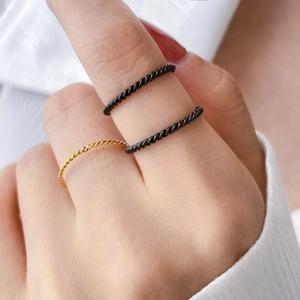 Macro detail of slim twisted rope rings in black and gold finish for stacked styling
