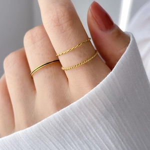 Close-up of three delicate gold stacking rings featuring twisted rope and smooth minimalist bands