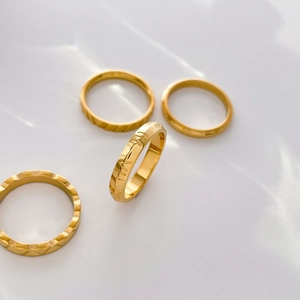 Detailed set of four 18K gold plated titanium rings with textured and engraved finishes