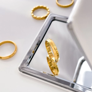 Detailed view of gold plated titanium steel ring with engraved Roman numerals on mirror