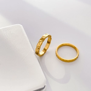 Detail of 18K gold titanium steel rings with geometric facets and vertical stripe textures