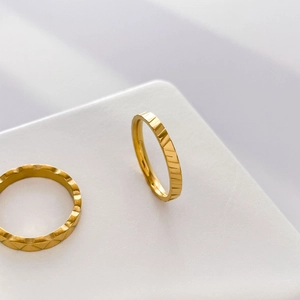 Close-up of gold 18K plated titanium steel rings showing geometric texture and ridges