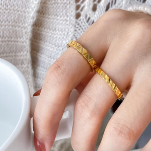 Close-up of gold geometric textured rings with triangle and diagonal line patterns