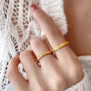 Close-up of gold titanium steel rings with geometric pyramid and linear faceted texture