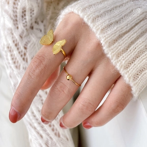 Detailed view of layered 18K gold plated butterfly and bead rings on female finger