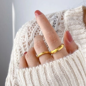 Detail of 18K gold-plated titanium rings with star engraving and cross-hatched texture