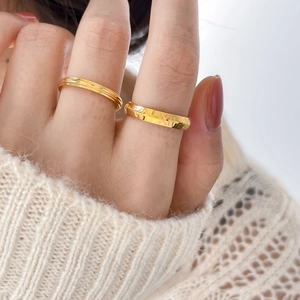 Close-up of gold titanium steel rings with Roman numerals and textured grooved designs