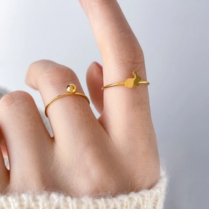 Detail of 18k gold plated titanium steel rings featuring cute bead and rabbit silhouette