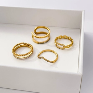 Ensemble de quatre bagues en acier titane plaqué or 18 carats avec zircons en écrin blanc