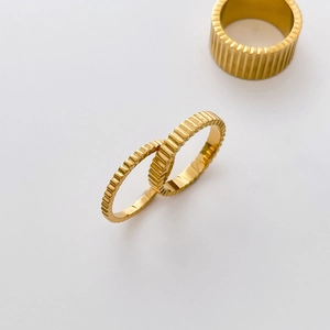 Close-up of three 18K gold plated gear rings with vertical texture and ribbed details