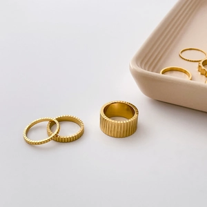 Detail showing vertical striped gold rings in wide and thin styles for stacking