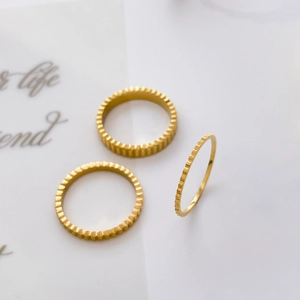 Detailed view of three 18K gold-plated titanium gear-styled rings in stacked arrangement