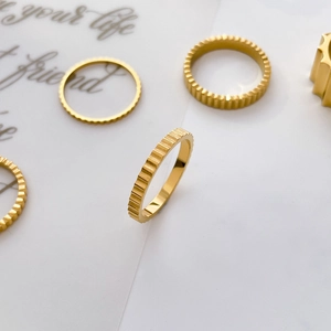 Detailed macro view of gold-plated titanium steel rings featuring gear texture and vertical grooves