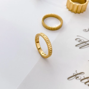 Detailed view of stackable gear-shaped titanium steel rings in an 18K gold-plated finish