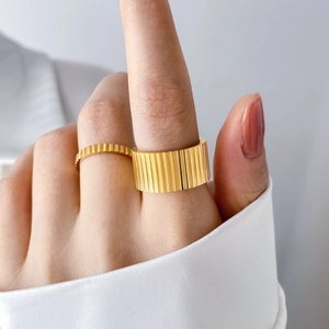 Close-up of stacked gold gear-shaped titanium rings with vertical striped texture details