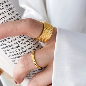 Gold plated titanium steel gear rings with vertical stripes worn by a model