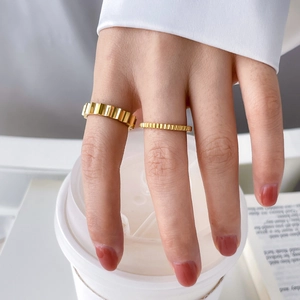 Detail of stacked 18K gold-plated titanium rings with vertical gear-like ribbed texture