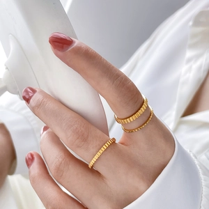 Detail of 18K gold-plated gear-style rings with vertical grooves and textured finish