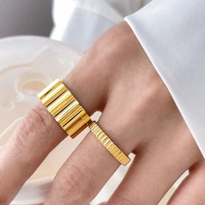 Detail of 18K gold-plated gear-shaped stackable rings with vertical striped texture