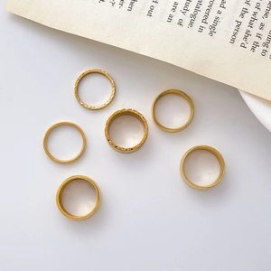 Detailed set of six gold titanium rings with hammered textures on vintage book background