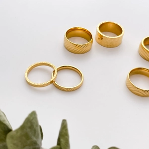 Minimalist 18K gold plated titanium rings with hammered and ribbed textures on white background
