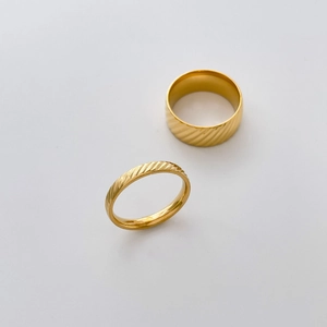 Detail view of gold fluted rings showing diagonal stripe engraving and mirror finish surface