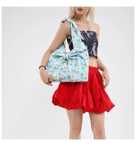 Macro view of blue floral tote bag showing bow pleat details and knitted 3D flower pattern