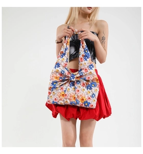 Detail of a floral print tote bag featuring a large decorative bow and daisy patterns