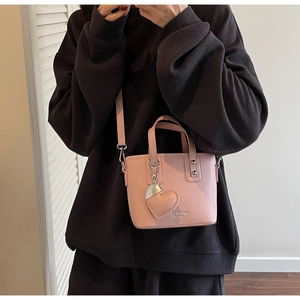 Detail of pink lychee leather bucket bag with silver metal hardware and heart pendant