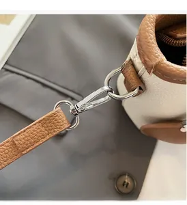 Detail of silver spring hook and D-ring on cream pebble leather bucket bag strap