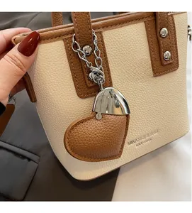 Detail of color-block leather bucket bag with silver chain and heart-shaped charm pendant