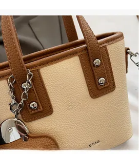 Close-up of litchi grain leather bag featuring silver rivets and heart-shaped charm