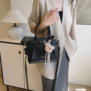Fashionable black lychee leather tote bag with a cute brown plush bear charm and strap