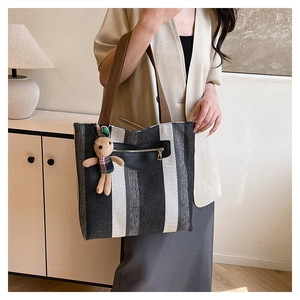 Detail of striped canvas tote bag with side zipper pocket and cute rabbit charm pendant