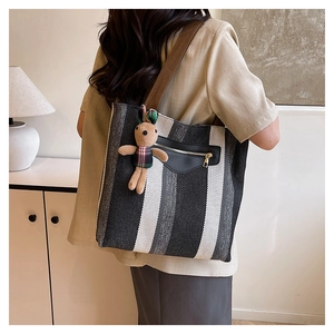 Vertical striped tote bag with brown strap and small rabbit charm shown on model