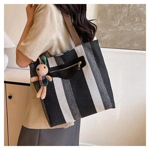 Macro detail of large striped tote bag featuring a black zipper pocket and cute rabbit charm
