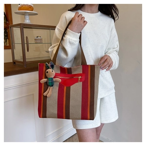 Detail of striped canvas tote bag with red leather pocket and cute rabbit charm