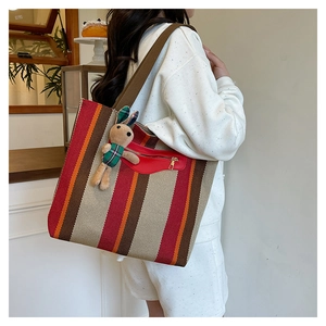 Close-up of striped canvas tote bag with front zipper pocket and cute rabbit charm