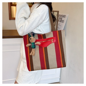 Detail of striped canvas tote bag with front zipper pocket and cute rabbit plush charm