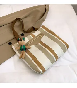 Detail of striped tote bag with cute rabbit charm and brown handles on cozy fabrics
