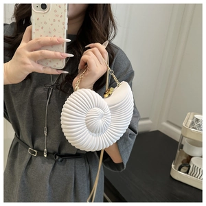 Detail of a white conch shell shaped bag with golden chain strap and spiral texture