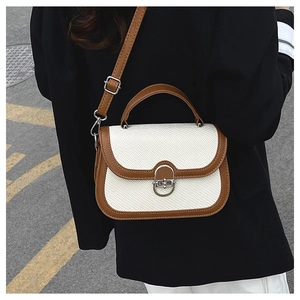 Detail of retro woven fabric handbag with brown leather trim and silver metal twist lock