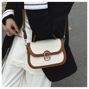 Detail of retro woven handbag showing beige texture, brown leather trim, and silver U-clasp