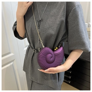 Detail of deep purple conch shell bag with spiral texture and gold chain strap