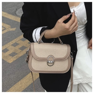 Detail of woven straw handbag with khaki leather trim and silver metal twist lock buckle