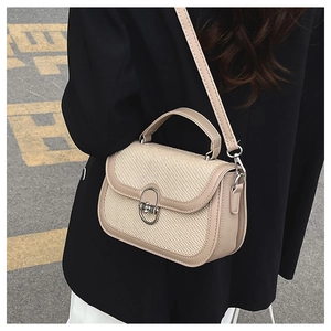 Close-up of woven patchwork handbag with metallic oval buckle and light khaki leather trim