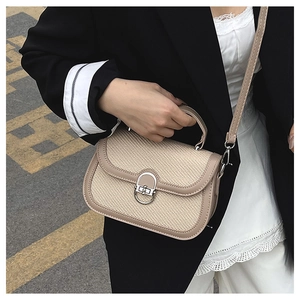 Detail of minimalist beige woven texture crossbody bag with silver twist-lock and handle