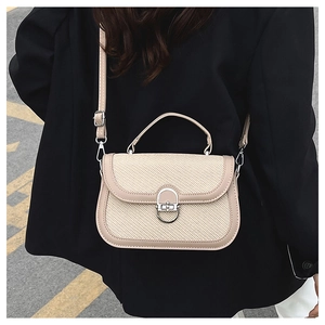 Detailed close-up of beige woven crossbody bag with silver U-shaped metal lock on suit