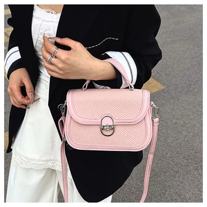 Detail of pink vintage crossbody bag with woven texture and round metal buckle detail